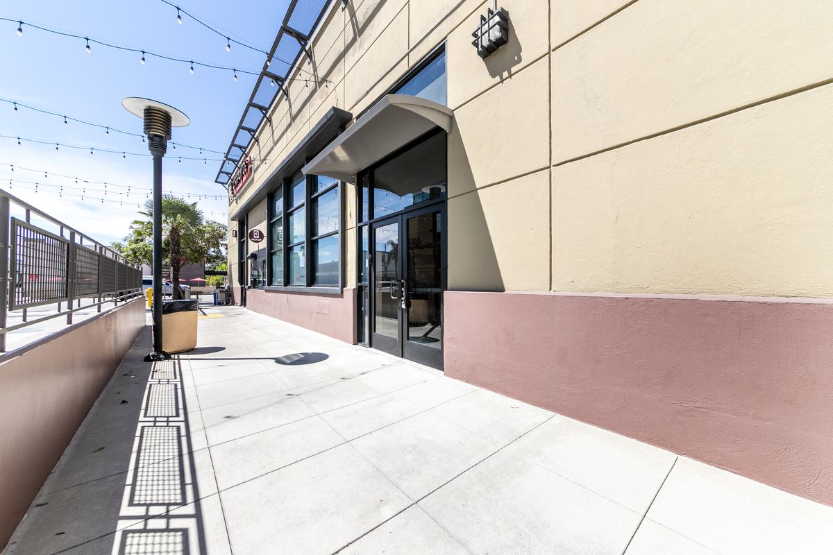 A recessed glass entrance with a curved awning on the Colorado Boulevard side of the corner building.