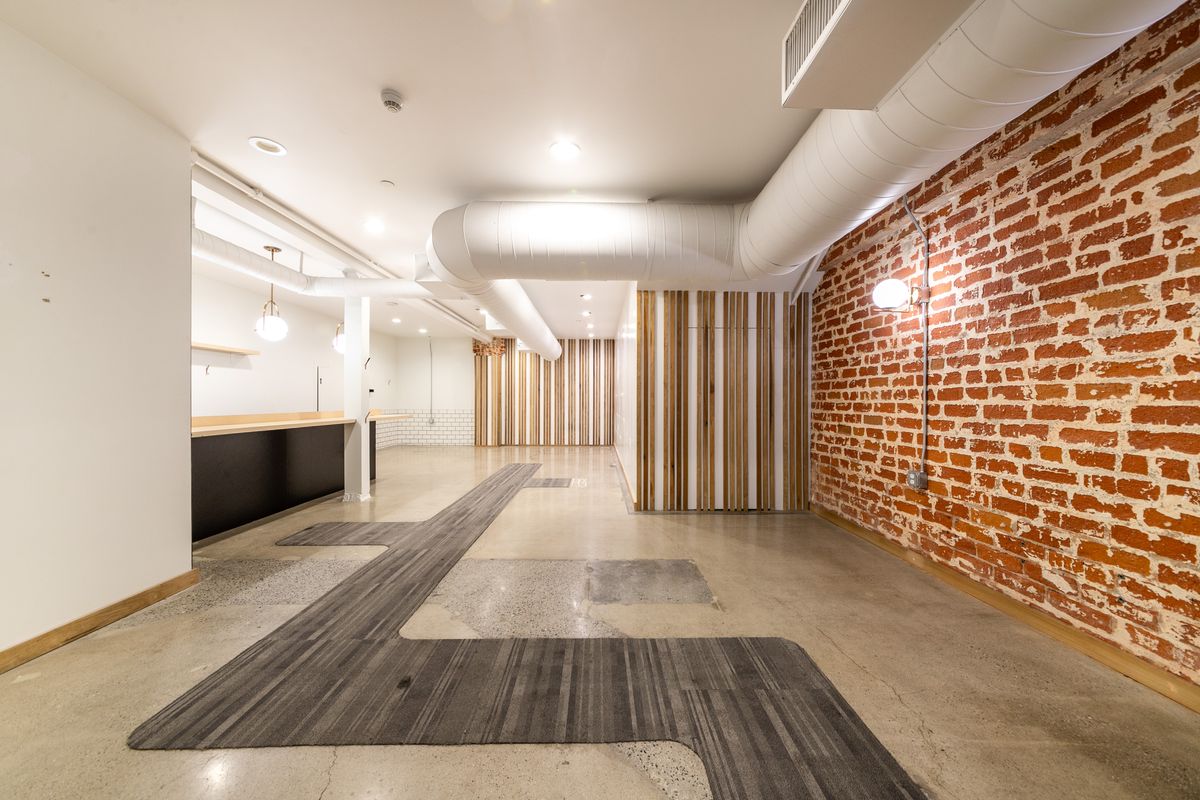 Suite 1 interior: exposed brick wall, wood-slat partition, and exposed ductwork.