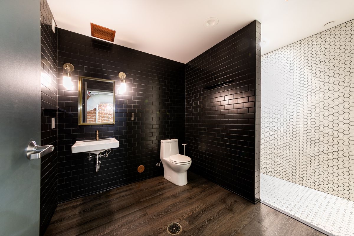 Suite 1 restroom with black subway tile and a hexagonal tile floor.