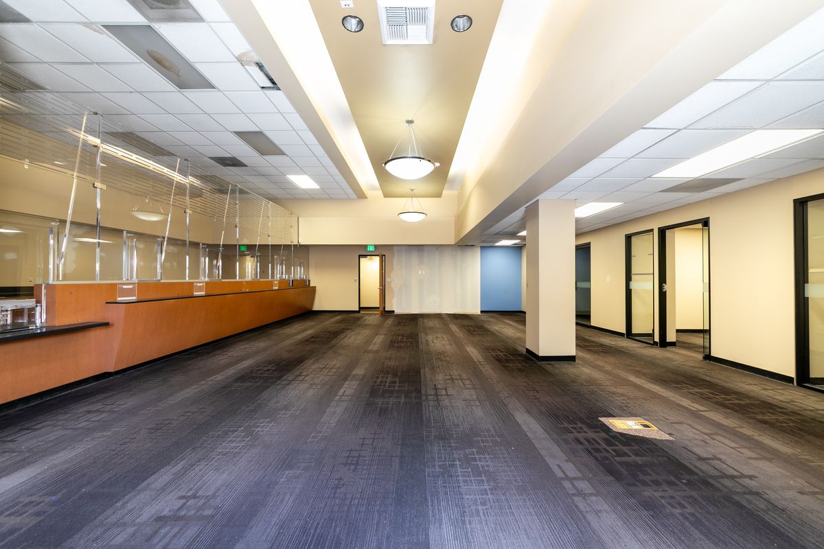 Suite 2 interior: the former bank lobby with a long wood-faced counter, glass partitions, and glass-walled offices along one side.
