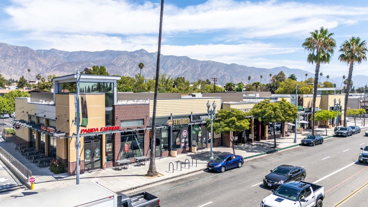 The west end of the main building with the two-story glass corner at Panda Express and sidewalk seating along Colorado Boulevard.