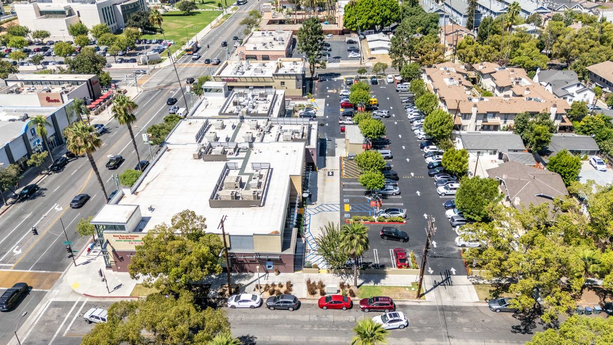 Aerial view of the surface parking lot behind the main building, with marked stalls, drive aisles, and trees.