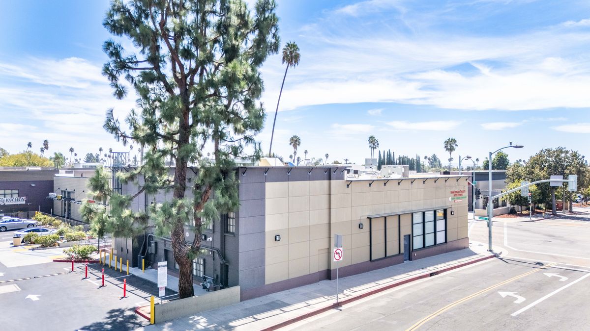 Suite 2, the former Bank of America building at the corner of Colorado Boulevard and Bonnie Avenue, seen from the parking lot with its taller charcoal-clad section and a pine tree in front.
